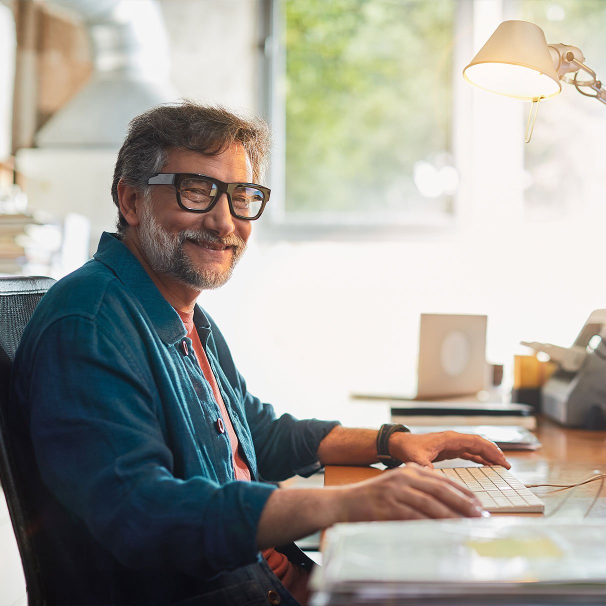 Elderly-man-with-glasses-smiling-and-using-PC