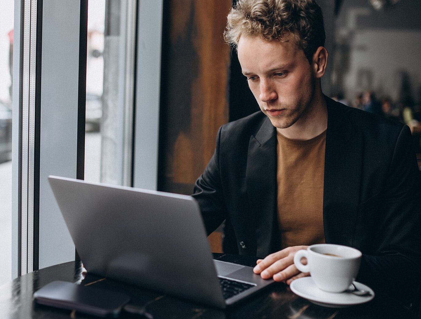 Young-man-using-laptop-with-external-harddrive-at-cafe